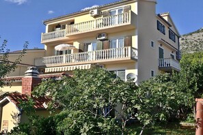 A multi-story residential building with balconies, air conditioning units, and a visible satellite dish.