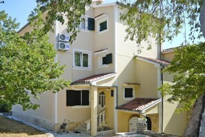 A multi-story building with a yellow facade, multiple windows, and a tiled roof. - Villa in Starigrad near Paklenica National Park (Starigrad Paklenica)