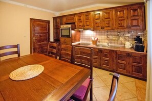 Uma cozinha com armários de madeira, uma mesa de jantar, cadeiras, micro-ondas e pia.
