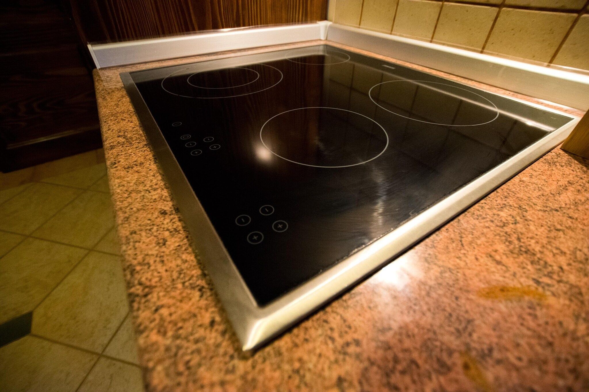 A kitchen with a black induction cooktop and granite countertops.