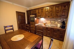 A kitchen with wooden cabinets, a dining table with chairs, a built-in oven, and a sink. - Villa in Starigrad near Paklenica National Park (Starigrad Paklenica)