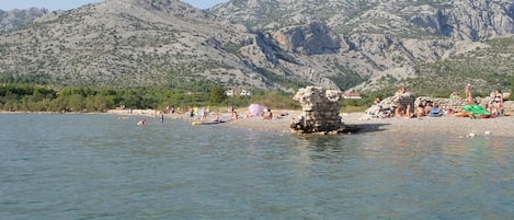 A beach with rocky terrain and mountains in the background.