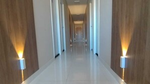 A long, well-lit hallway with wooden paneling on the walls and a shiny tiled floor. - Hotel la Sierra (Bodoquena)
