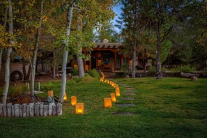 A rustic lodge with a stone pathway leading to the entrance, surrounded by trees and a wooden fence. - Green Acres Luxury Estate on 4 Acres 8m to Plaza! (Santa Fe)