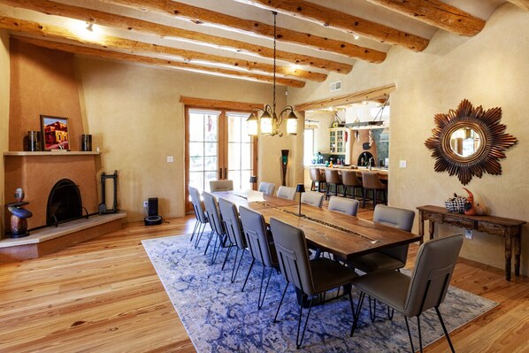 A spacious dining area with a long wooden table, modern chairs, and a rustic fireplace. - Green Acres Luxury Estate on 4 Acres 8m to Plaza! (Santa Fe)