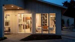 A modern house with a large glass door leading to a living area with a sofa and chairs. - Modern Luxury - Carmel (Carmel-by-the-Sea)