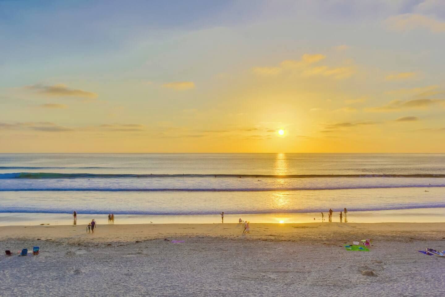 Una spiaggia al tramonto, con onde e persone.