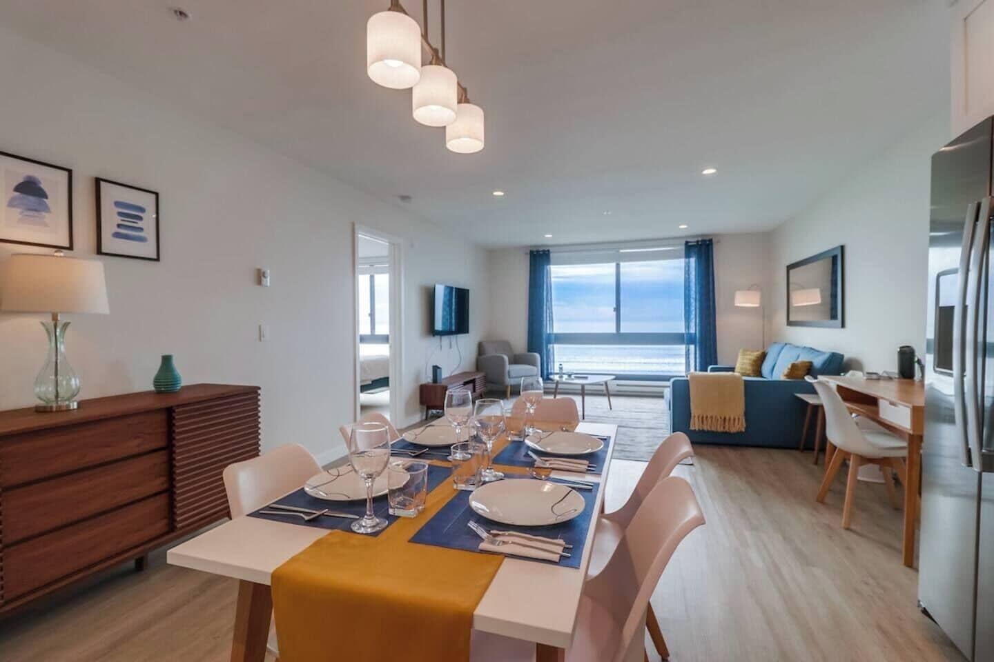 Een moderne eetruimte met een tafel voor vier personen, een bank en uitzicht op zee.