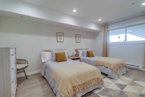 A hotel room with two beds, a wardrobe, a chair, and a large window.