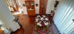 Un coin repas avec une table ronde dressée pour six personnes, entourée de chaises. Un buffet en bois aux portes vitrées se trouve à l’arrière-plan.