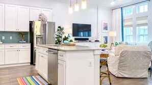 Una cocina moderna con armarios blancos, una isla central, horno empotrado y ventilador de techo.