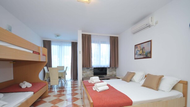 Una habitación de hotel con literas, una cama individual, un televisor, una chimenea y un comedor.