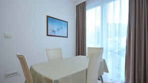 Un comedor con una mesa y sillas, un cuadro en la pared y vistas a través de amplias ventanas.