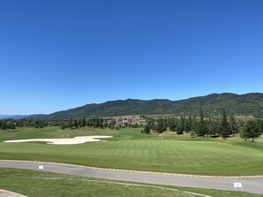 Een golfbaan met een clubhuis, een weg en een berg op de achtergrond.