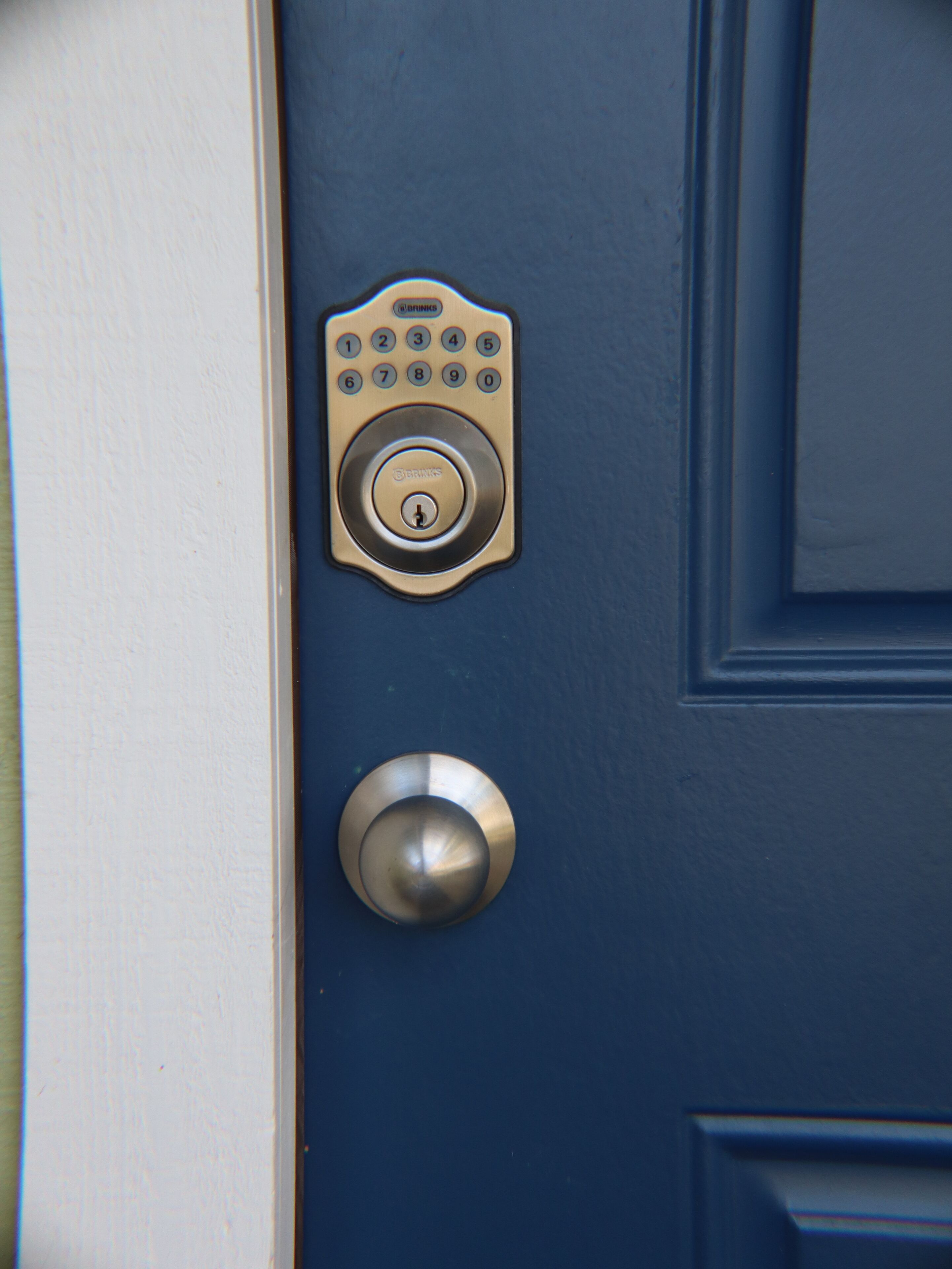 A blue door with a keypad lock and a round doorbell.