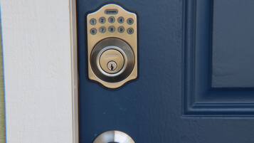 A blue door with a keypad lock and a round doorbell.