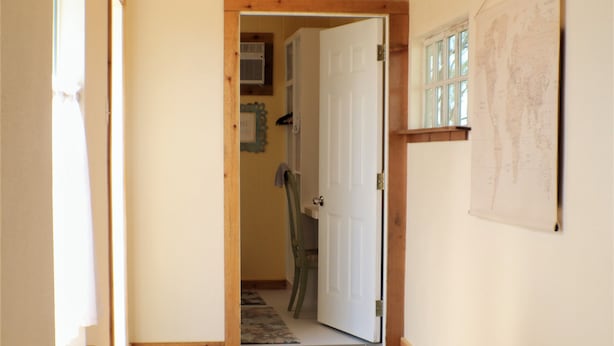 Un couloir avec un banc en bois, une porte donnant sur une autre pièce et une carte accrochée au mur.