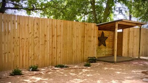 Une clôture en bois ornée d’une découpe en forme d’étoile, une structure abritée et de petites plantes.