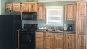 A kitchen with wooden cabinets, a black refrigerator, a microwave, a stove, and a sink.