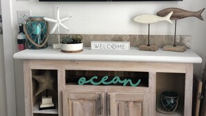 A wooden entertainment center with a TV mounted above it, decorated with a starfish, a fish, and a welcome sign.
