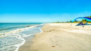 Ein Strand mit blauem Himmel, sandigem Ufer und einem blauen Sonnensegel.