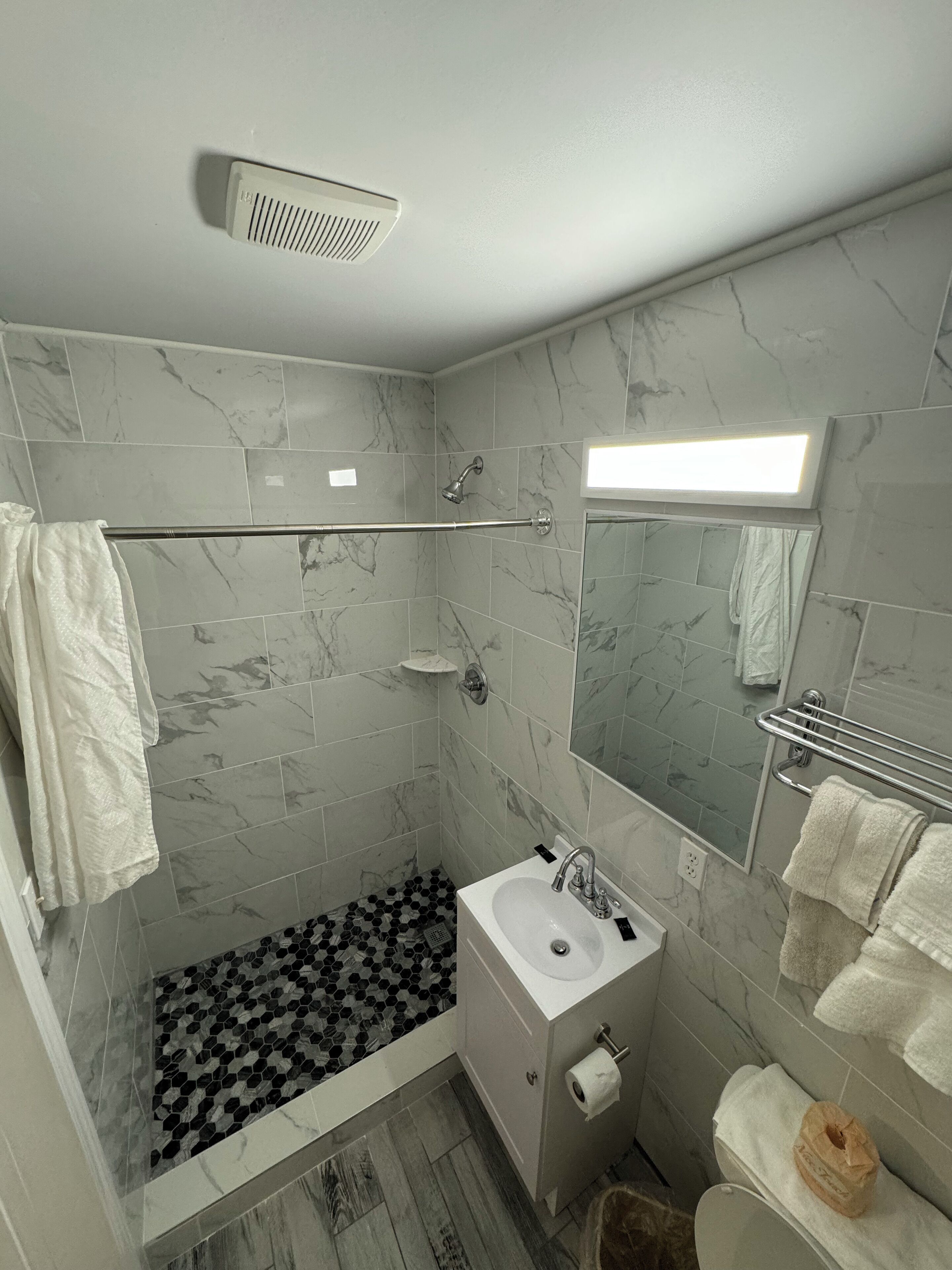 A modern bathroom with a shower, sink, and toilet.