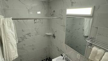 A modern bathroom with a shower, sink, and toilet.