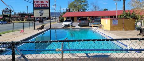 A motel with a swimming pool, a sign advertising daily rates, HBO, and WiFi.