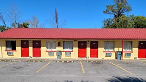 Un motel con techo rojo y puertas numeradas.