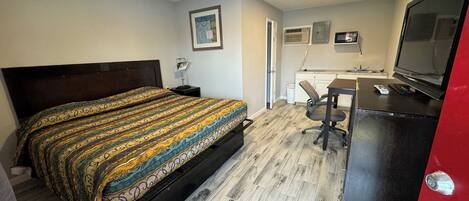 A bedroom with a bed, a desk, a chair, a television, and a wardrobe.