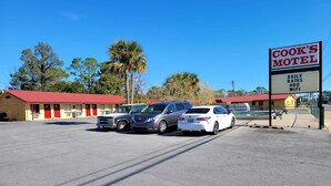 Un motel con techo rojo, un letrero y varios coches estacionados.