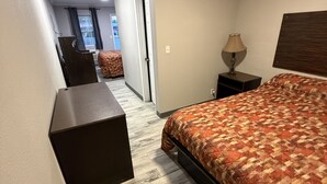Un dormitorio con cama, escritorio, silla, mesita de noche y lámpara.