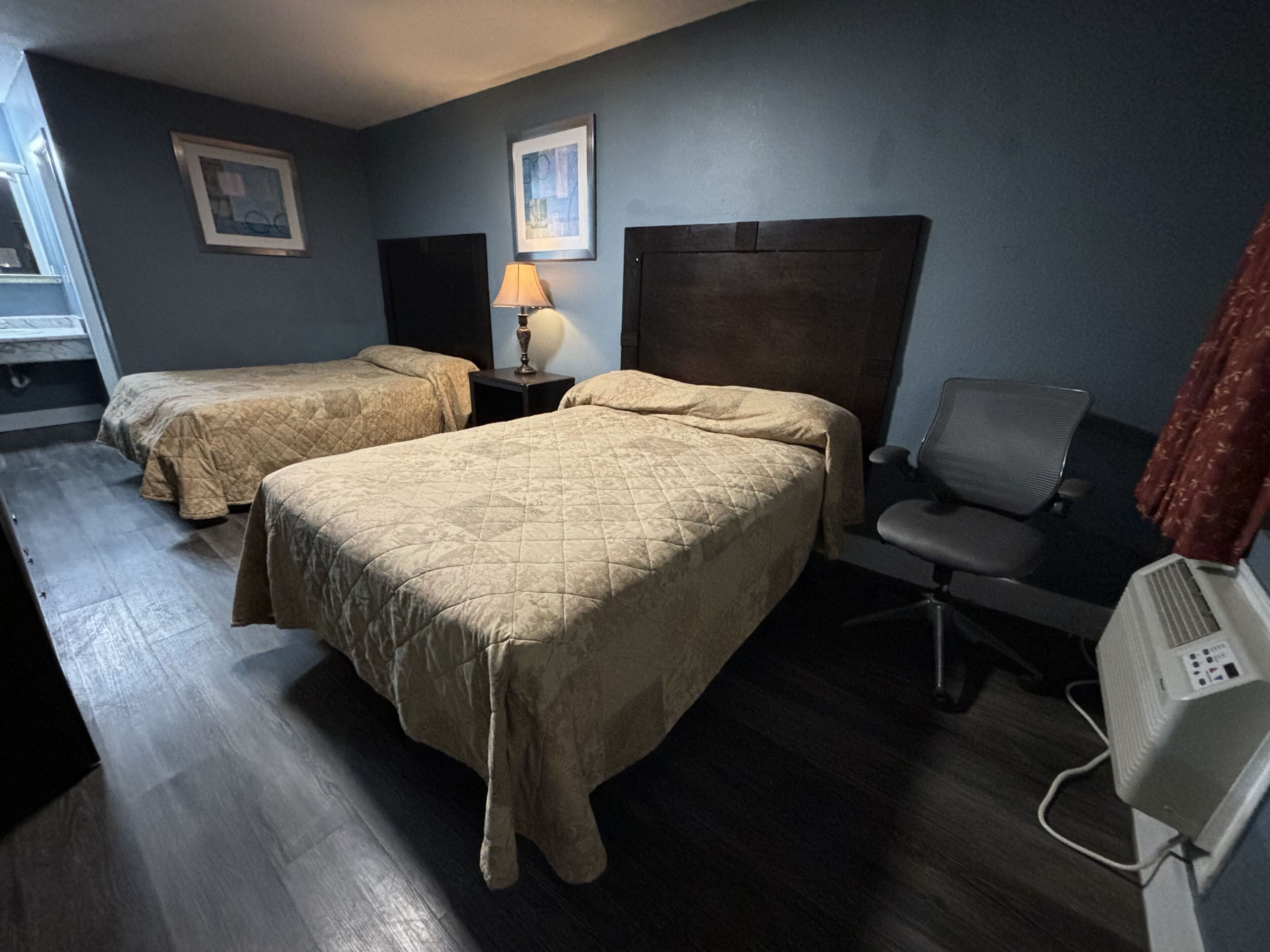 Habitación de hotel con dos camas, un escritorio, una silla y un calentador.