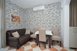 Une pièce avec un mur décoré de motifs, un canapé, une table à manger avec des chaises et un appareil de climatisation.