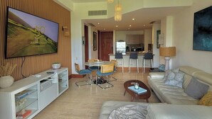 Ein modernes Wohnzimmer mit Flachbildfernseher, einer Couch, einem Couchtisch und einem Essbereich mit Stühlen und Tisch.