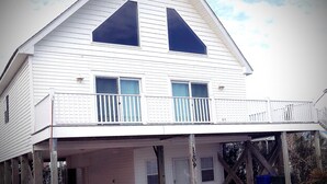Een wit huis met twee verdiepingen, een balkon, een garage en een houten terras.