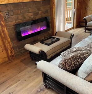 Cozy living room with a fireplace, comfortable sofa, and exposed wooden beams.