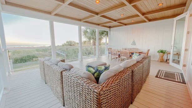 Un balcon spacieux avec des meubles en osier, de grandes fenêtres et une vue sur la plage.