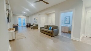 Relax in this spacious living area with a sofa, table, and sliding glass door leading to a balcony.