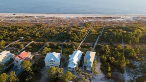 Une vue aérienne d’une propriété située sur la côte, avec plusieurs maisons, une plage et un ciel dégagé.