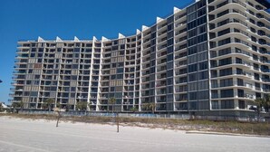 Et hotel med flere etager og balkoner, beliggende tæt på en strand.
