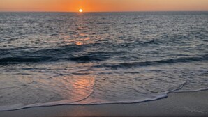 Ein Sonnenuntergang über einem ruhigen Meer mit sanften Wellen.
