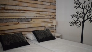 A bedroom with a wooden headboard, white bedding, and a wall decal of a tree. - Anacasa Dianium Ausias March AP1112 (Denia)