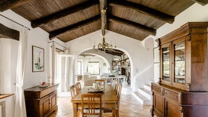 Un comedor amplio con una mesa y sillas de madera, una araña y un gran aparador de madera.