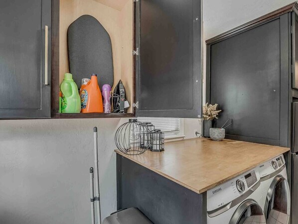 A compact kitchen with a washing machine, a wooden countertop, and various kitchen items.