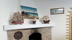 A brick fireplace with three model ships on top. - The house of the Sirolo gecko (Sirolo)