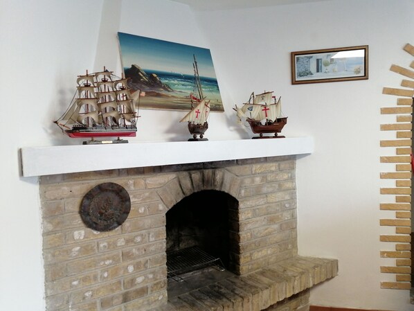 A brick fireplace with three model ships on top.