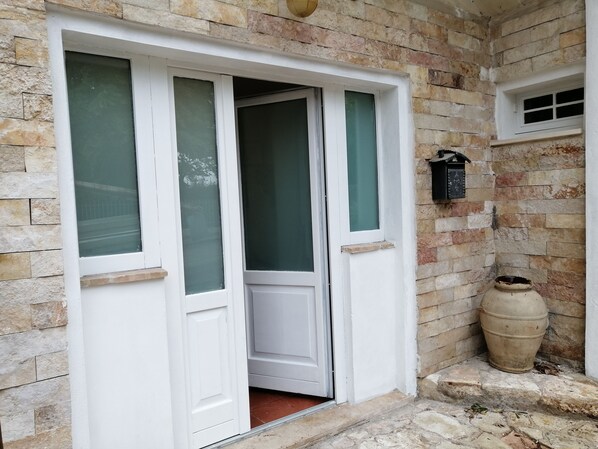A white door with frosted glass panels, set in a stone wall with a small window above.
