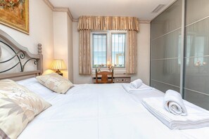 A hotel room with a bed, a desk, a chair, and a large window with curtains.