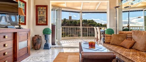 A spacious living area with a balcony, a television, and a sofa.
